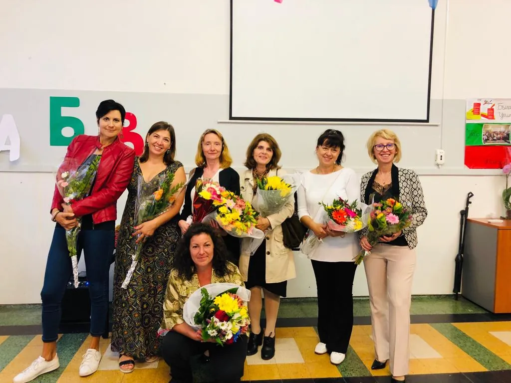 Le insegnanti della scuola con i fiori, davanti alle lettere dell'alfabeto cirillico